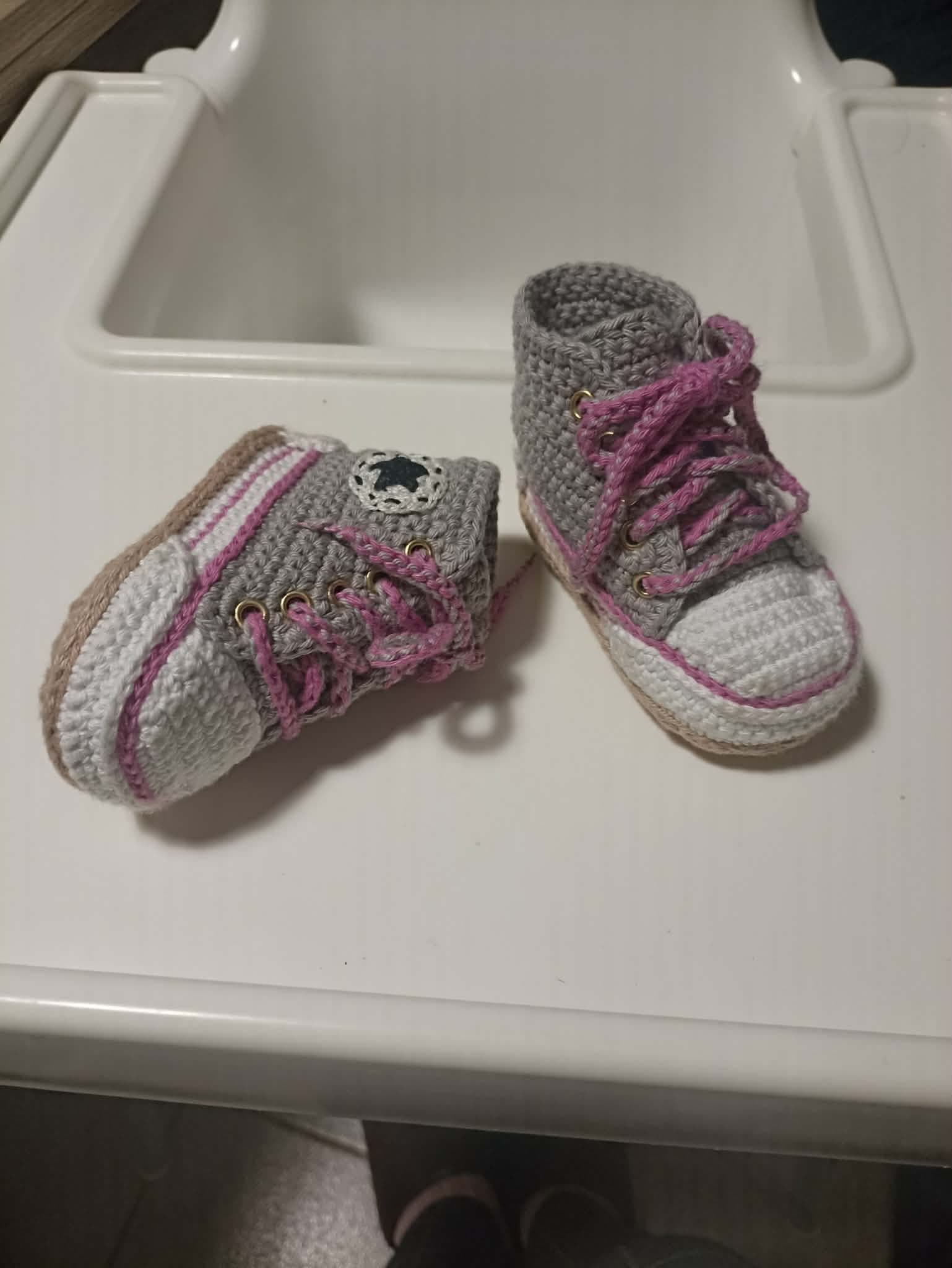Baby crochet booties, high-cut, with pink laces and a beige sole.